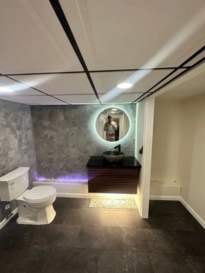 Bathroom renovation featuring floating vanity with LED lighting and round mirror.