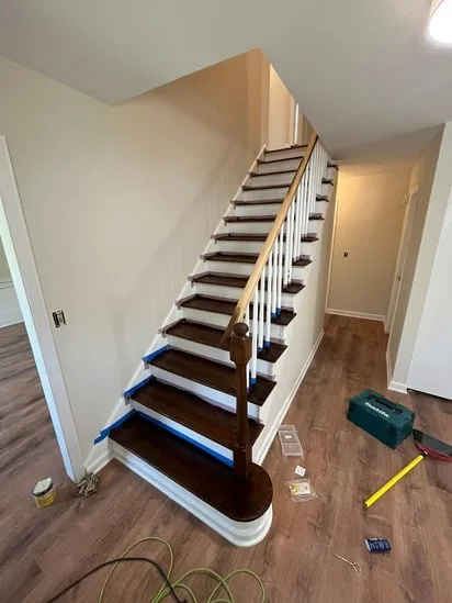 Completed wood stair refinishing with dark stained steps and white risers.