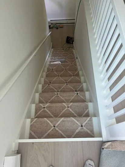 Completed stair carpet installation with geometric patterned runner.